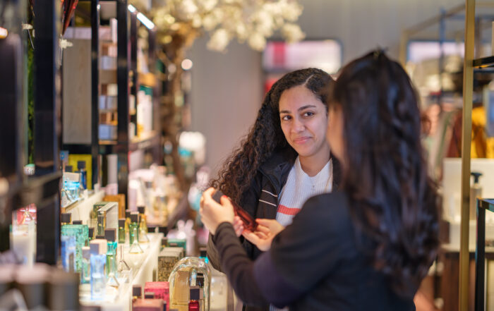 En ung kvinna får hjälp av butikspersonal att välja parfym