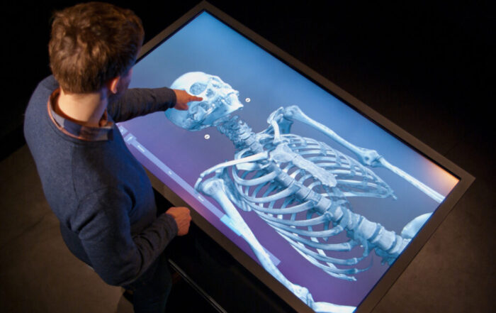 En man pekar och visar en stor skärm som visar ett skelett med VR-teknik