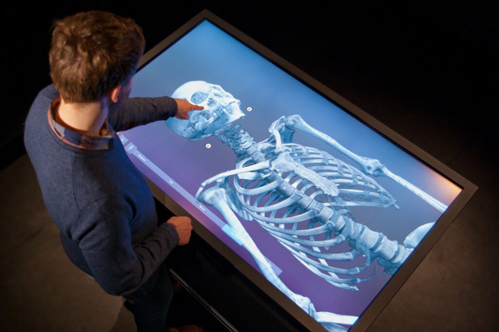 En man pekar och visar en stor skärm som visar ett skelett med VR-teknik